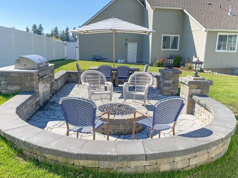 Circular paver seating area with a gas fire pit and stone kitchen island built by Elite Hardscapes in Spokane, WA