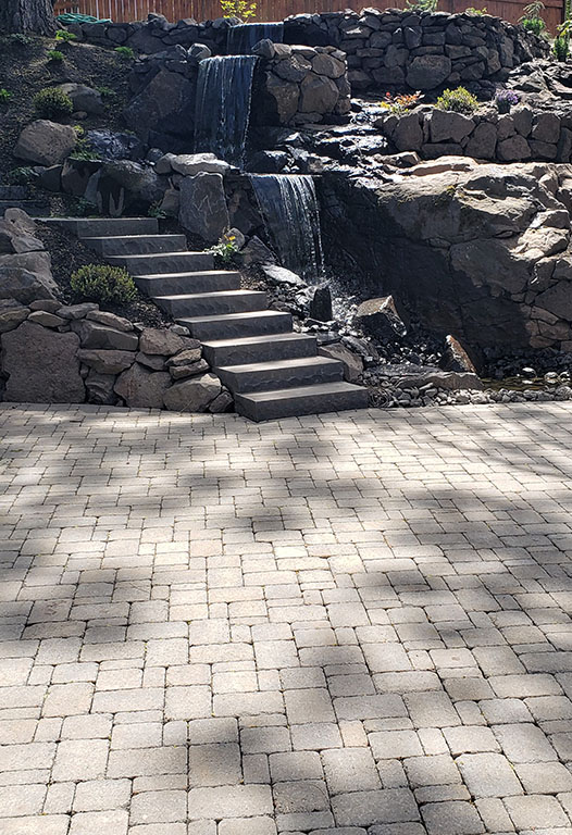 Landscaped garden beds with layered planting and stone edging by Elite Hardscapes in Spokane, WA