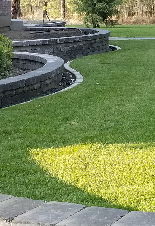 Completed residential landscape with lawn, beds and stone walkway by Elite Hardscapes in Spokane, WA