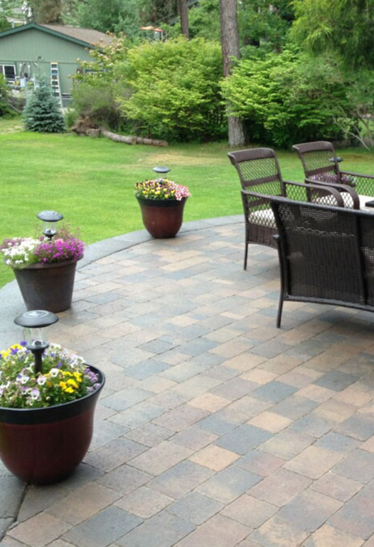 Warm landscape lighting illuminating a stone pathway and planting beds at dusk in Spokane, WA