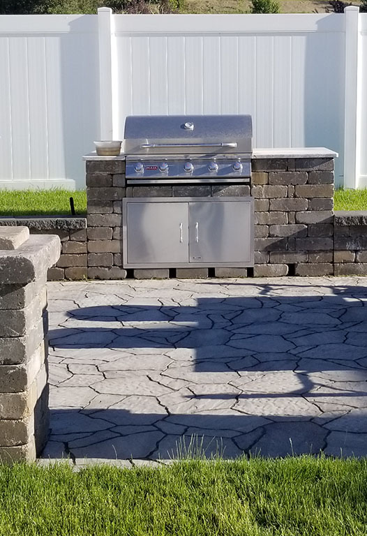 Stone outdoor kitchen island with built-in grill and lighting built by Elite Hardscapes in Spokane, WA
