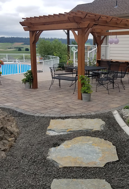 Large paver patio with outdoor furniture and fire pit built by Elite Hardscapes in Spokane, WA