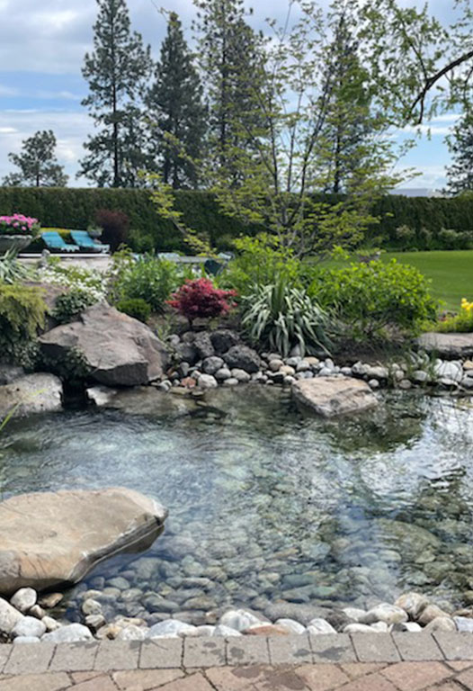 Natural rock waterfall and pond with surrounding planting built by Elite Hardscapes in Spokane, WA